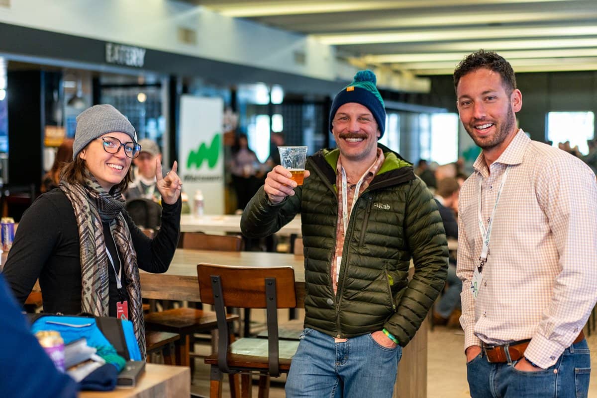Three attendees laughing together at the bar